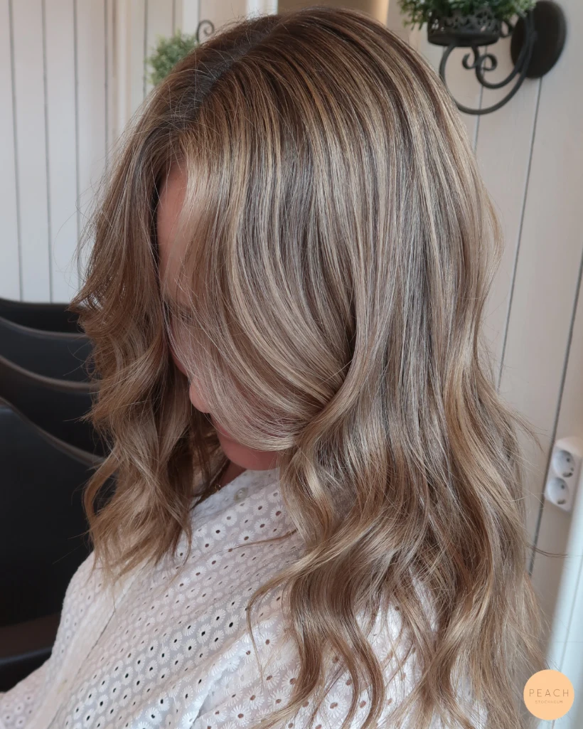 Beige blond hårfärg med ljusa slingor och rootshadow och mjuka teasylights