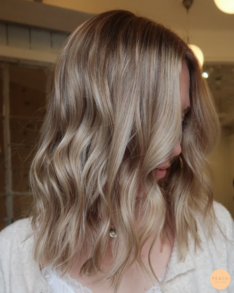 Beige blond hårfärg med ljusa slingor och mjuk root shadow