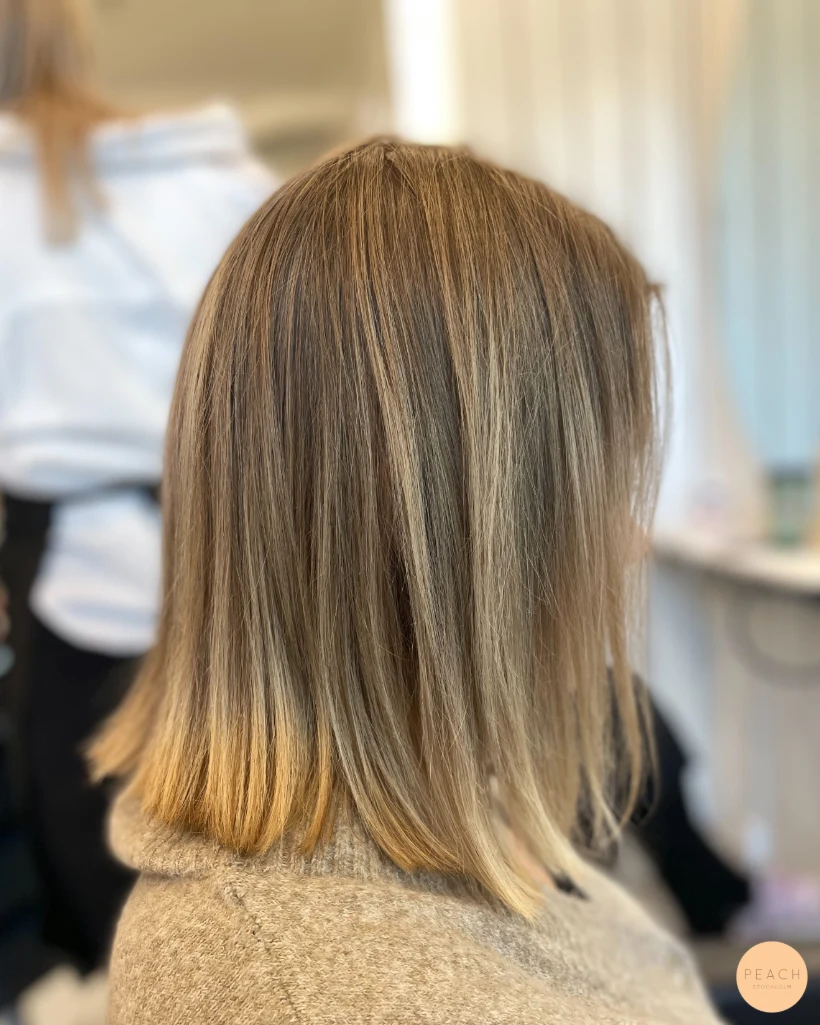 Kall blond hårfärg med ljusa slingor och mjuk root shadow