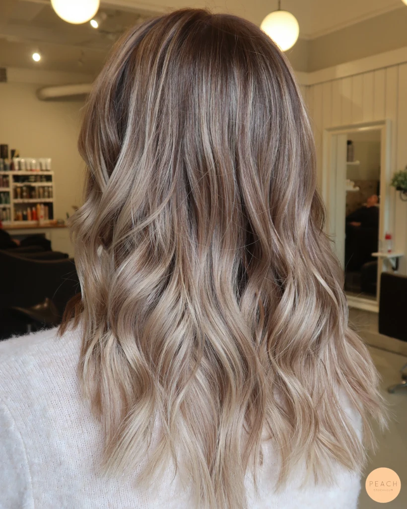 Beige blond hårfärg med ljusa slingor och mjuk root shadow