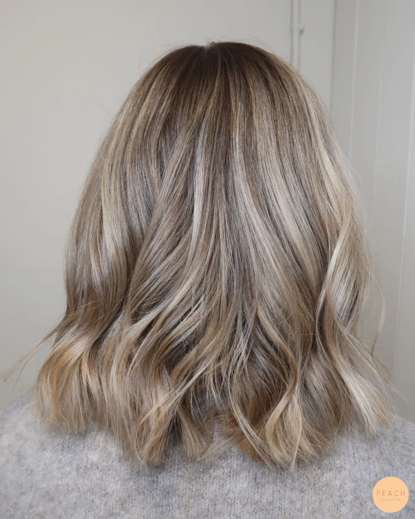 Kall blond hårfärg med ljusa slingor och rootshadow och mjuka teasylights