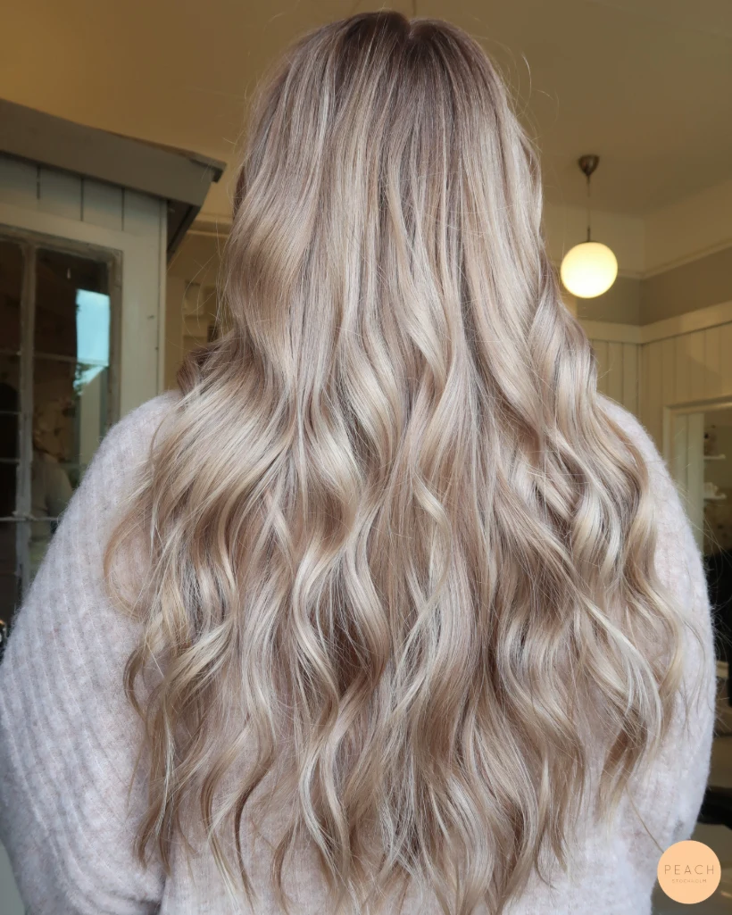Beige blond hårfärg med ljusa slingor och rootshadow och mjuka lowlights