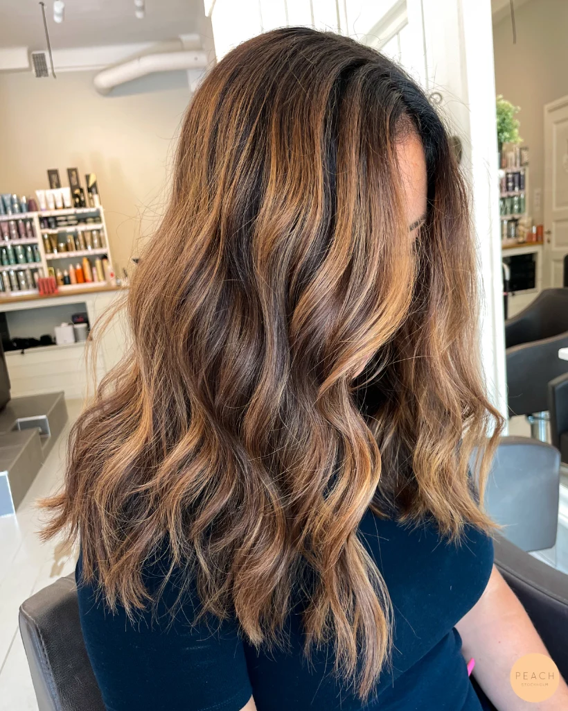 Karamellbalayage med varma slingor i brunt hår