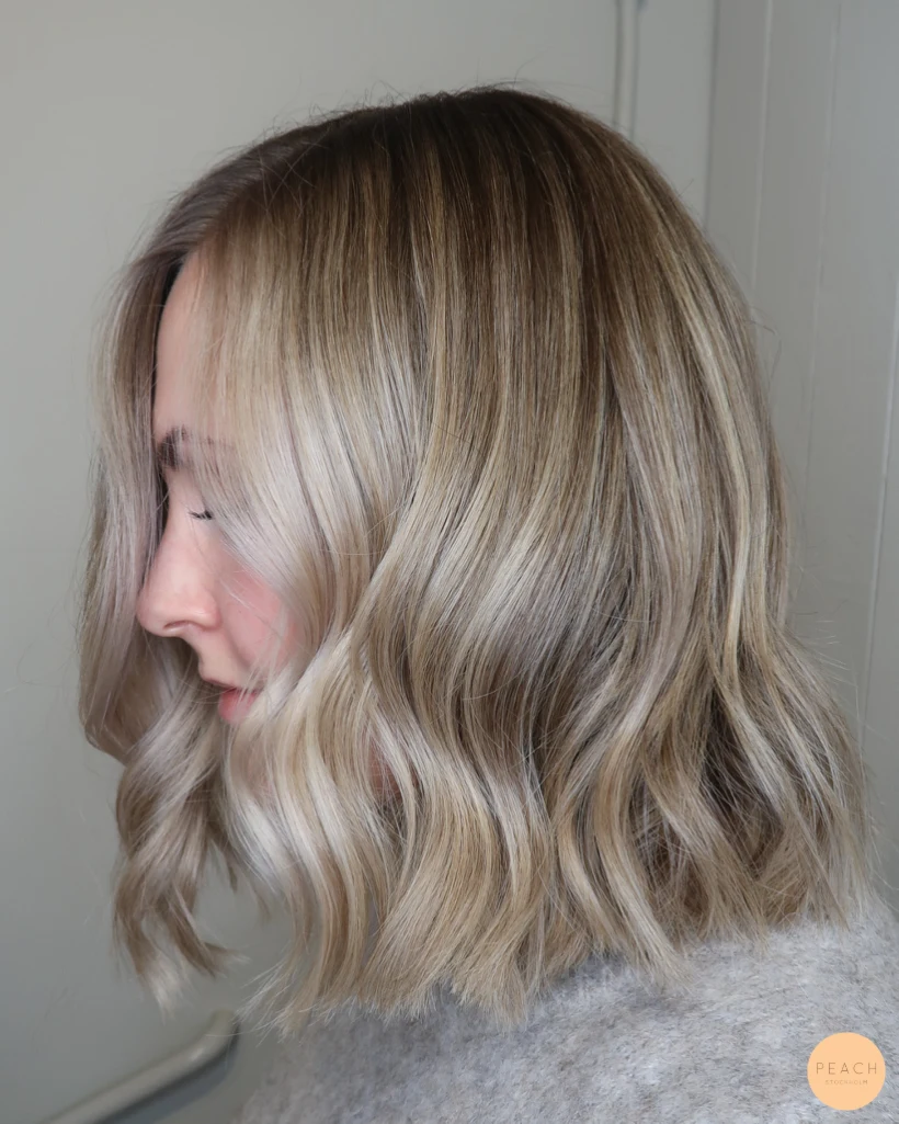 Kall blond hårfärg med ljusa slingor och rootshadow och mjuka teasylights