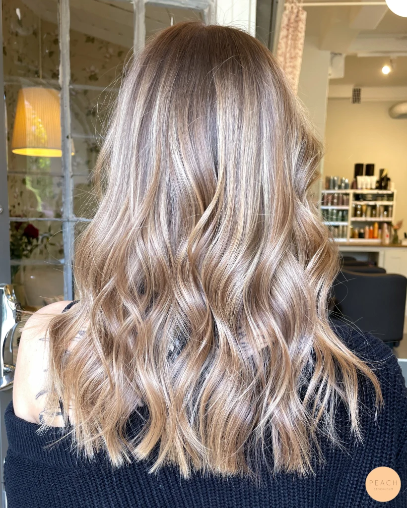 Mellanblond hårfärg med ljusa slingor och mjuk root shadow
