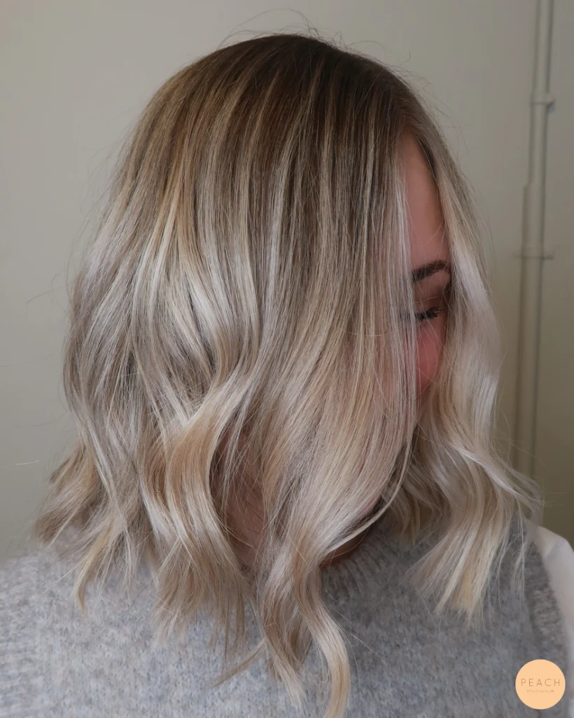 Kall blond hårfärg med ljusa slingor och rootshadow och mjuka teasylights