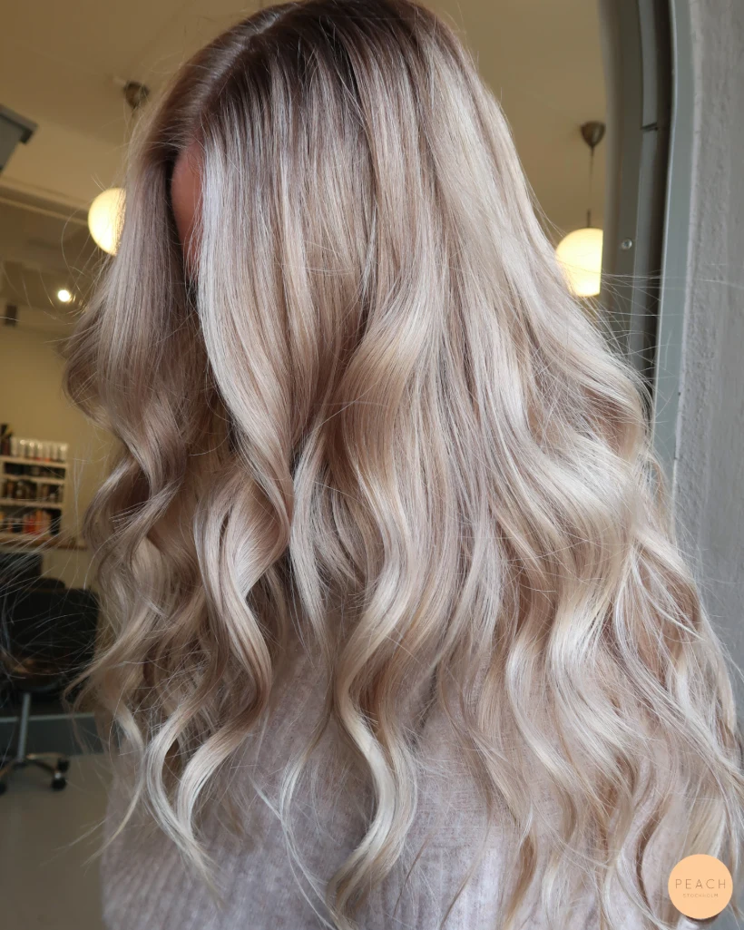 Beige blond hårfärg med ljusa slingor och rootshadow och mjuka lowlights